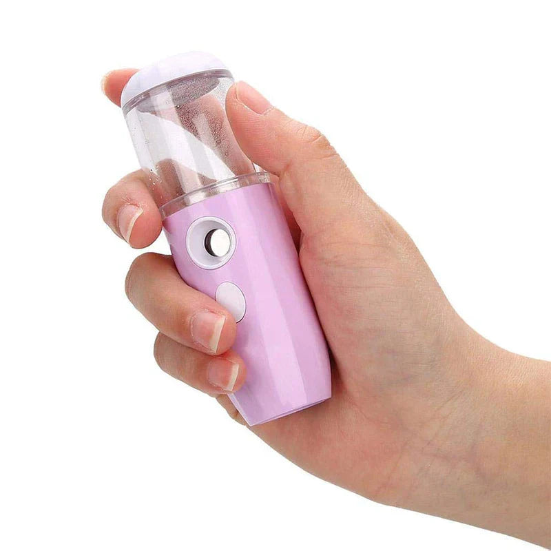 Nano Mist Facial Sprayer - Light pink handheld mist sprayer held in a person’s hand, with moisture visible inside its clear tank
