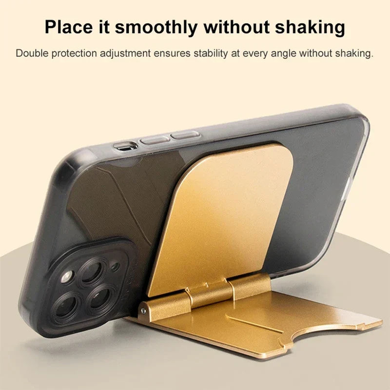 Cell Phone Holder - Gold foldable phone stand holding a black smartphone with text above about stable placement.