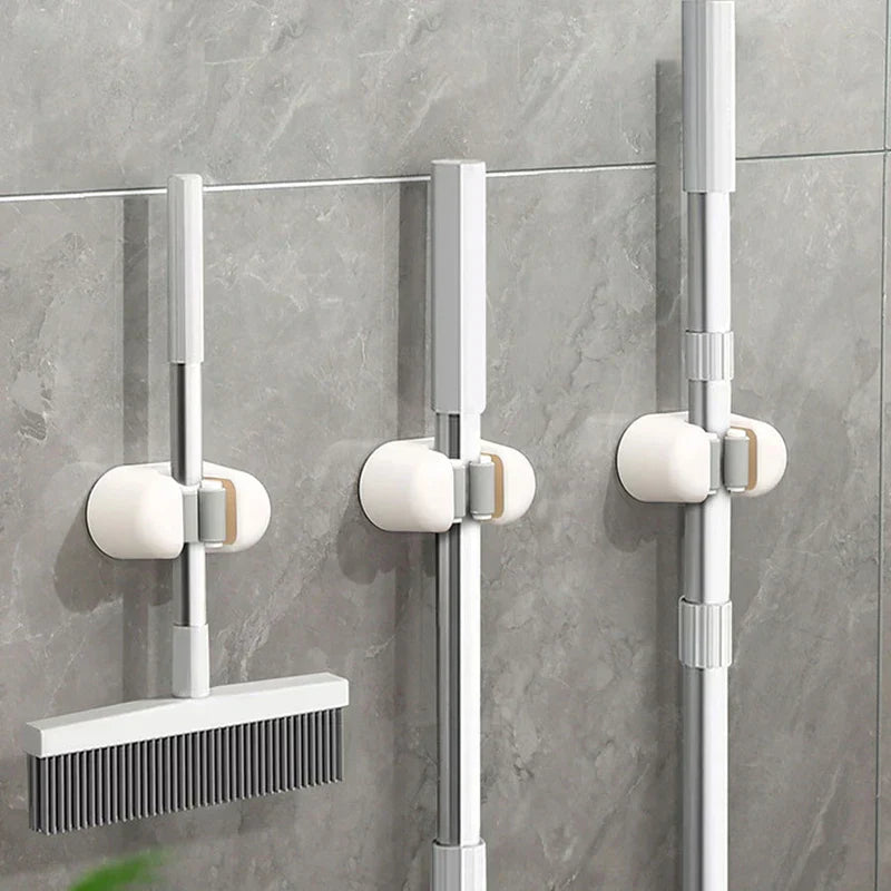 Utility Tool Storage Gripper Hanger System - Three installed holders mounted on gray tile wall holding long-handled cleaning tools