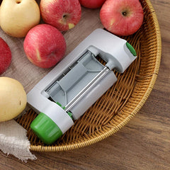 Vegetable Sheet Slicer Ribbon Cutter Tool - Closed gray fruit peeler with green knobs rests in a wicker tray alongside red and yellow apples