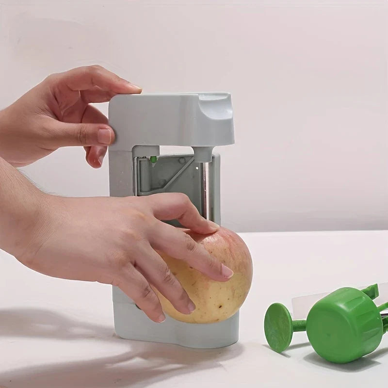 Vegetable Sheet Slicer Ribbon Cutter Tool - Two hands position an apple onto the upright peeler, with the extended green handle and detached cap placed nearby