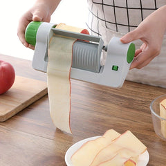 Vegetable Sheet Slicer Ribbon Cutter Tool - Hands holding a manual fruit slicer peeling a red apple, with peeled apple slices on a plate below.