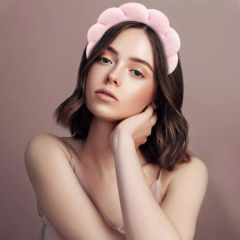 Velvet Padded Sponge Headband Hair Hoop - Woman in pink camisole wears pink cloud-shaped headband, resting cheek on hand against plain mauve background