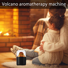 Aroma Diffuser Humidifier - Black and clear two-tone aromatherapy device with simulated volcano graphic sitting on a fur rug, with an adult and child sitting by a fireplace in the background.
