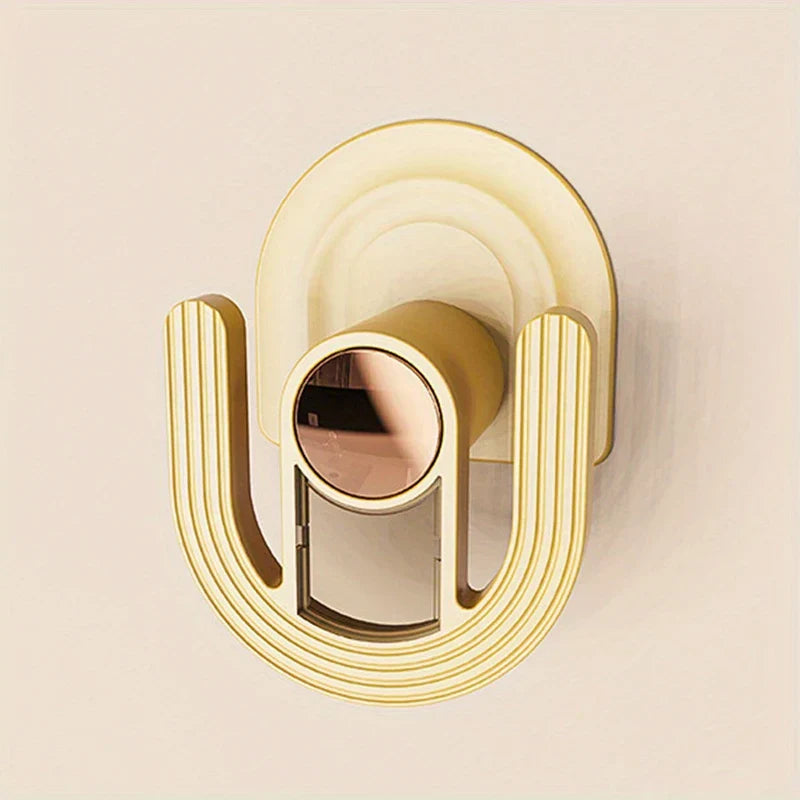 Slipper Rack Organizer - Close-up of a cream and gold U-shaped adhesive wall hook with rose gold center accent on a plain light wall