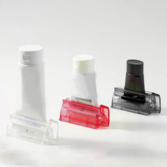 Wall Mount Toothpaste Dispenser - Three tube squeezers in clear, red and smoky gray, each holding a different cosmetic tube, against a white background