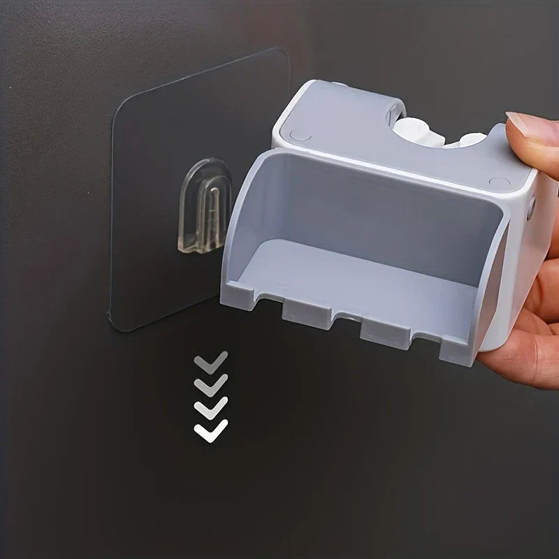Mop And Broom Holder - Hand holding a gray wall holder, aligning it to a clear adhesive wall hook with downward arrows indicating sliding installation