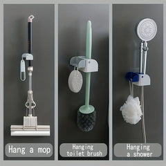Mop And Broom Holder - Three side-by-side wall holders mounted on a wall, holding a mop, toilet brush, and handheld shower with hanging accessories respectively