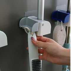 Mop And Broom Holder - Hand hanging a small cleaning brush from the side hook of a gray wall holder holding a pole, with a second holder visible in background