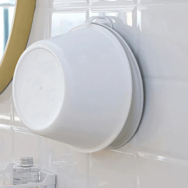 Two white and gray basins hang stacked on a hook attached to a glossy tiled wall; a wash basin storage rack is mounted on the tile holding the basins.
