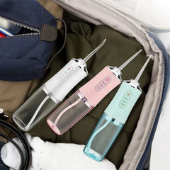 Water Flosser - Three portable water flossers in white, pink, and mint placed inside an open travel bag