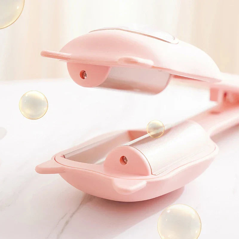 Egg Roll Maker - Open pink handheld appliance resting on a white marble surface with translucent bubble accents around its heating plates