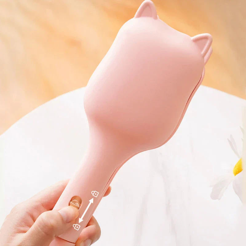Pink cat-shaped egg roll maker held in a hand, showing its sliding lock switch on the handle