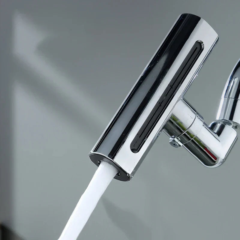 Close-up of a tilted chrome faucet sink extender with a steady stream of water flowing from its outlet.