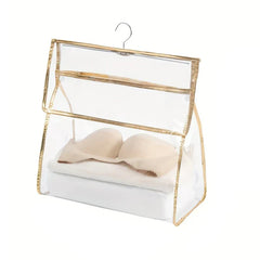 Shower Organizer - Clear hanging storage bag with gold trim holding a beige bra and folded linens, fitted with a metal hanging hook