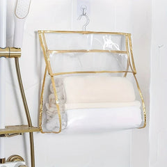 Shower Organizer - Clear gold-trimmed hanging bag holding folded towels, hung on a wall hook next to a shower fixture