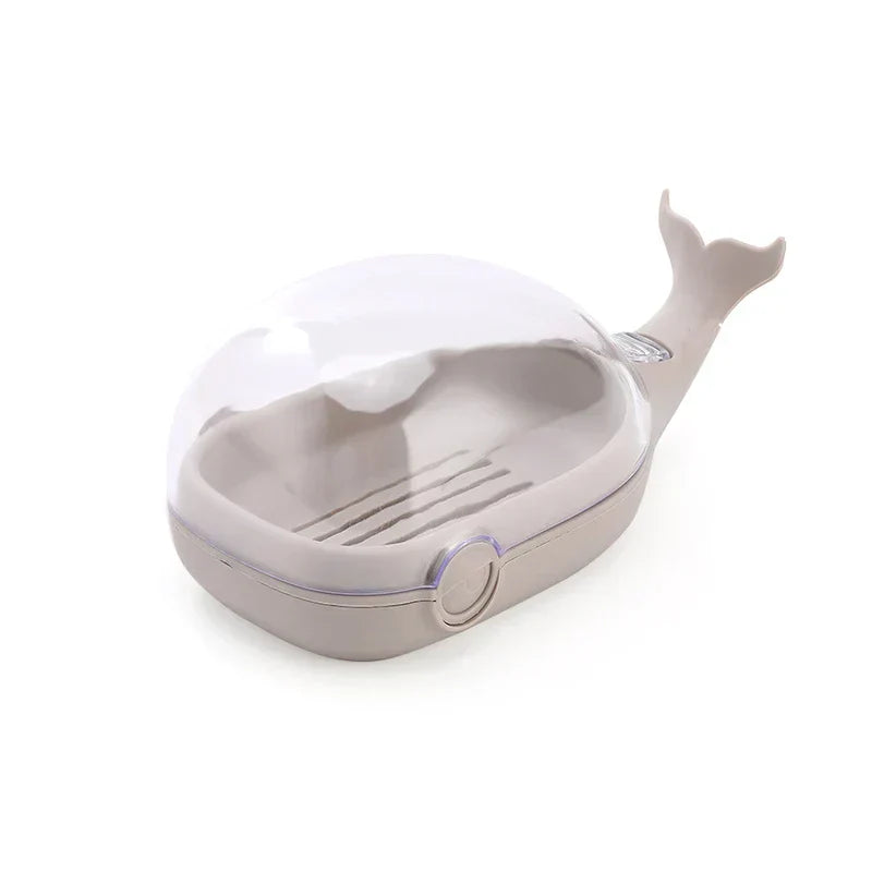 Closed light gray whale-shaped soap dish with clear dome lid, slotted interior, and tail-shaped extension