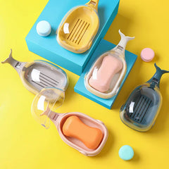 Soap Dish - Multiple whale-shaped soap dishes in different colors, some open with soap inside, arranged with small macarons