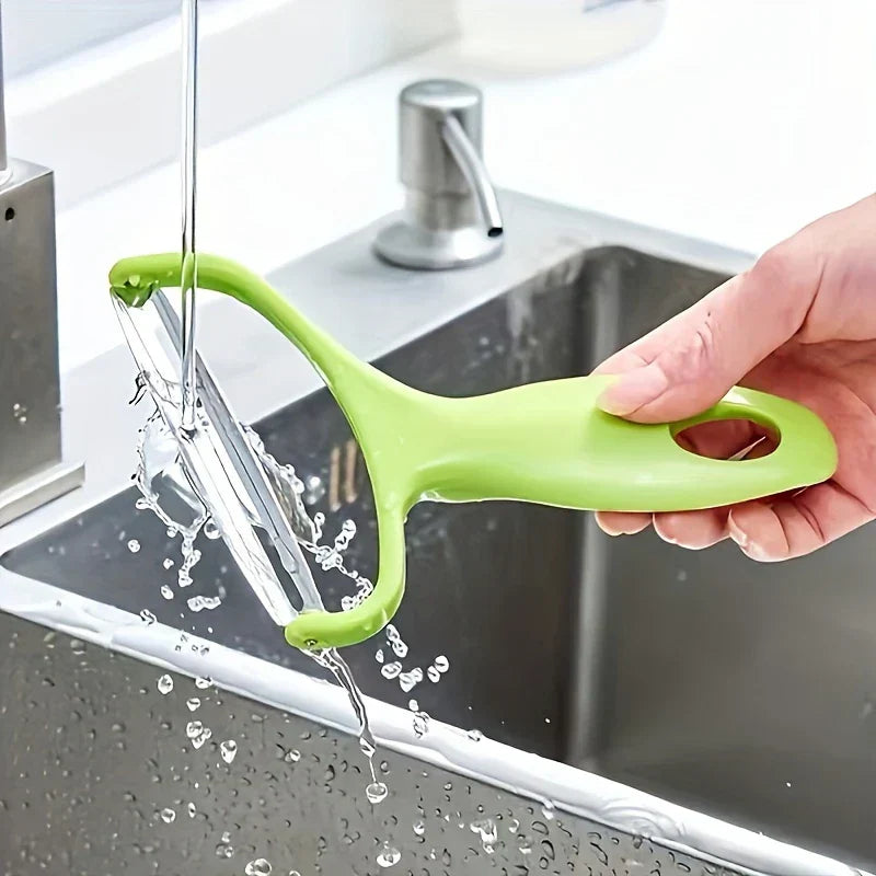 Vegetable Slicer - Hand holding a green vegetable peeler under running tap water over a sink, water splashing.