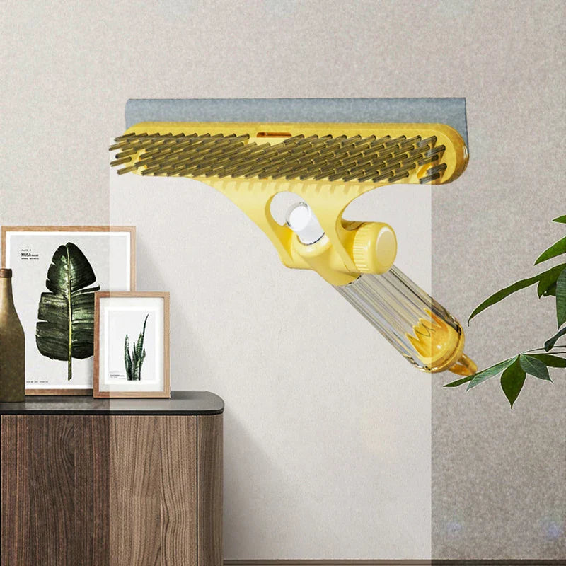 Herramienta limpiadora de ventanas: vista lateral de la herramienta de limpieza manual amarilla que muestra el lado de cerdas, descansando sobre panel de vidrio junto a gabinete de madera con decoración enmarcada