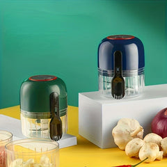 Garlic Mincer - Two cordless electric choppers in green and navy displayed on raised platforms next to fresh whole garlic, onion, and mushrooms