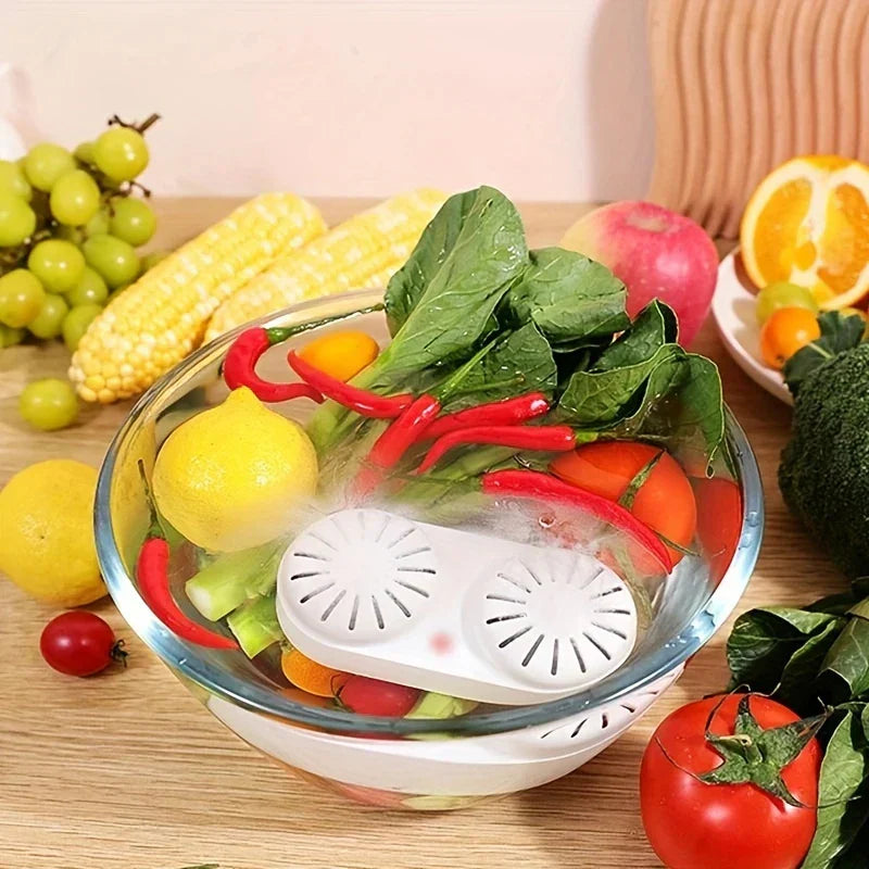 Fruit Vegetable Purifier Washer Capsule - White dual-core device submerged in a glass bowl of water with assorted fruits and vegetables, on a wooden table