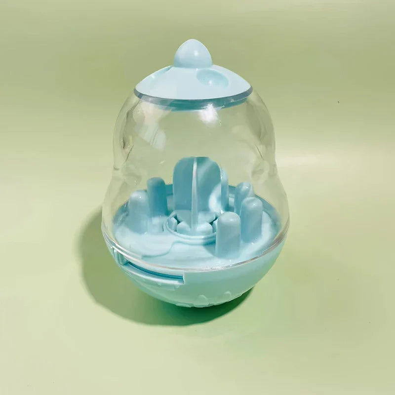 Interactive Pet Toy - Empty light blue plastic and clear tumbler-style pet treat toy with internal posts, resting on a light green surface