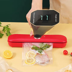 Mini Bag - Hand holding a red vacuum sealer's control panel showing '11', sealing a bag with fish and lemon slices on a beige surface