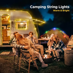 Camping String Lights - A family sits around a campfire near a lit caravan and tent with warm string lights at night