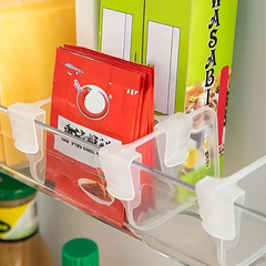 Adjustable Fridge Dividers - Clear plastic fridge shelf dividers holding stacked red seasoning packets next to a green wasabi box
