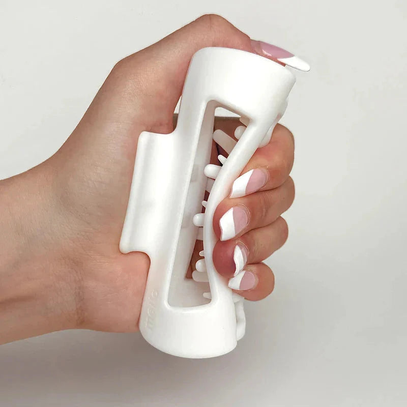 Cloud Clip - Hand holding a closed white hair claw clip, with pink and white French tip fingernails visible.