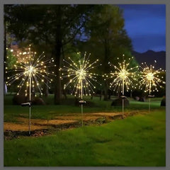 feenlichter - Vier solarbetriebene Garten-Feenlichter mit wunderkerzenartig leuchtenden Glühbirnen stehen bei Dämmerung entlang eines Gartenpfads.