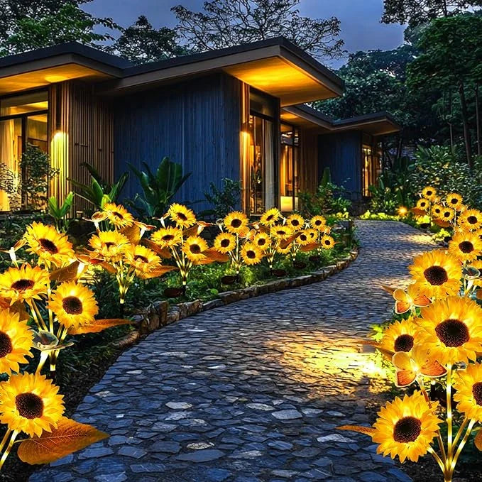 Sunflower Garden Lights - Illuminated sunflower-shaped solar garden lights lining a paved stone path outside a house at dusk