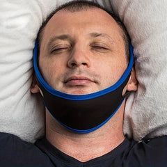 رجل مستلقٍ على وسائد وعيناه مغمضتان، ويرتدي حزام ذقن باللونين الأسود والأزرق حول فكه