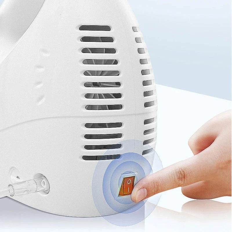 Close-up of a finger pressing the orange power switch on a white handheld fine mist atomizer device with vent slits.