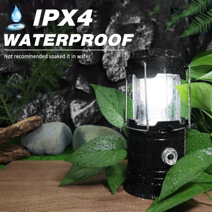 Lit black camping lantern with water droplets on it, surrounded by wet green leaves, text reads IPX4 WATERPROOF and Not recommended soaked it in water