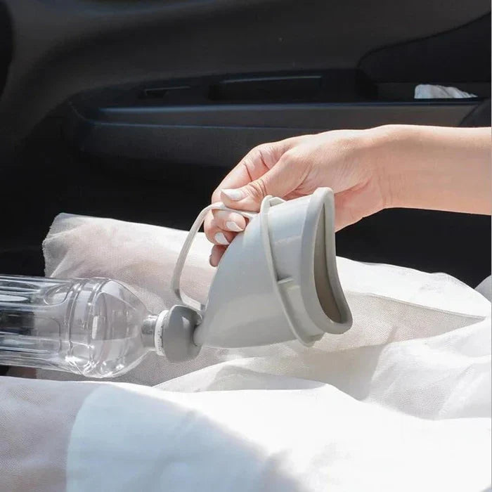 Portable Travel Urinal - Hand holding light gray travel urinal attached to a clear bottle, resting on white fabric in a car