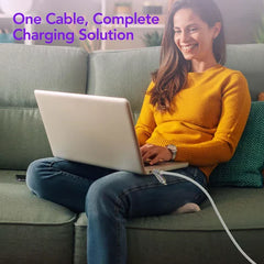 Woman sitting on a couch using a laptop that is plugged in with a 4 in 1 usb charging cable