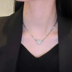 Magnetic Love Patchwork Necklace - Close-up of a person’s neck wearing a silver-toned necklace with a whole, rhinestone-covered heart pendant at center, black v-neck top