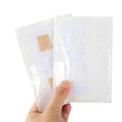 Emergency Wound Closures Device - A hand holding two sealed transparent packages containing adhesive skin closure strips