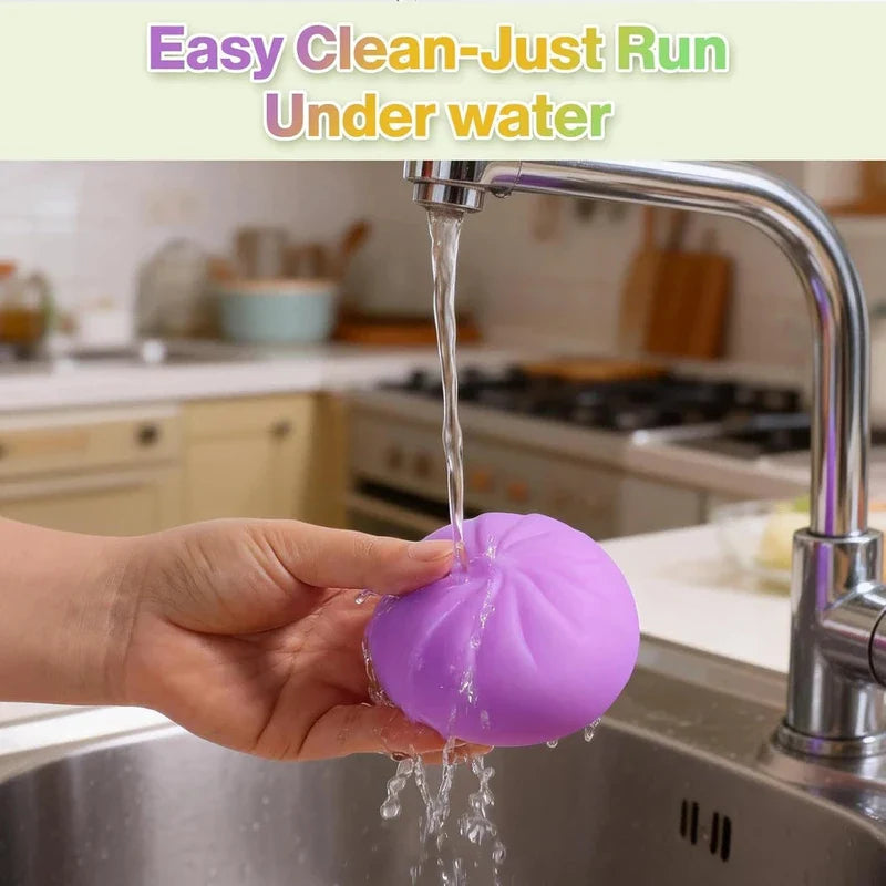 Stress Relief Toy - A hand holds a purple bun-shaped object under running water from a kitchen faucet to clean it