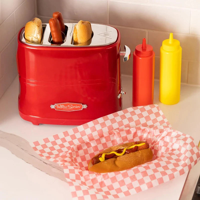 Retro hot dog toaster (red, Retro Series) with buns and sausages, plus a prepared hot dog, ketchup, and mustard bottles on a counter