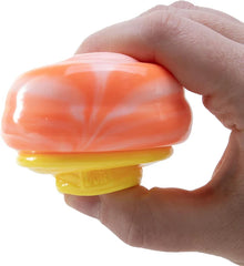 juguete sensorial - Mano aprieta el juguete sensorial NeeDoh Nice Cream con remolino naranja mármol, mostrando su forma comprimida