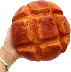 ananasbrot quetschspielzeug - Eine Hand mit einem Perlenarmband hält ein rundes, gerilltes Ananasbrot-Quetschspielzeug vor einem schlichten weißen Hintergrund