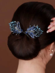 Pfauenfeder Haarschmuck - Blaue Kristall- und silberne Pfauenfeder-Haarklammer in einem braunen tiefen Dutt befestigt