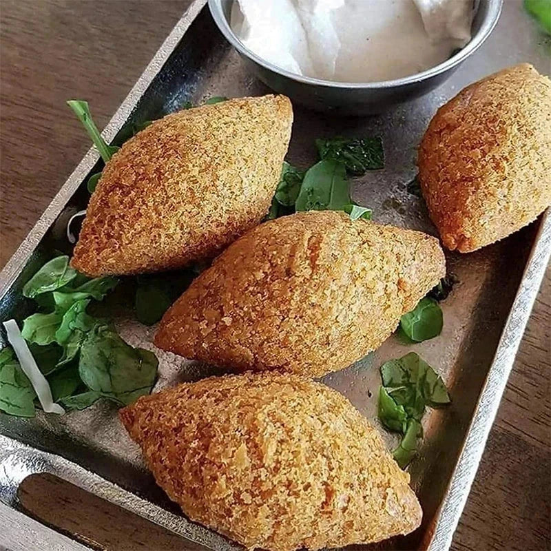 طقم أدوات خبز - أربع قطع طعام بيضاوية محشوة ومقلية ومغطاة بالبقسماط على صينية معدنية، مع خضار ووعاء صغير من صوص التغميس الأبيض.