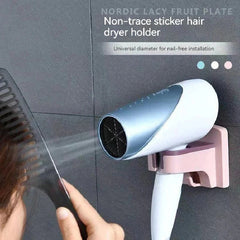 haartrockner ständer - Eine Person kämmt sich die Haare, während ein Haartrockner in einem rosa Badezimmer-Haartrocknerhalter sitzt, der an einer dunkelgrau gefliesten Wand montiert ist.