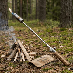 Camping Long Flame Igniter - igniter with lit flame positioned next to a small campfire on forest ground with canvas storage pouch