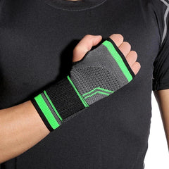 Compression Palm Hand Brace Glove - A person wearing a black shirt has a gray, black, and bright green knit wrist and palm support on their hand held to their chest.