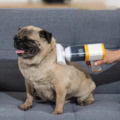 Car Vacuum Cleaner - Hand holding a small handheld vacuum against a sitting pug dog on a gray fabric couch